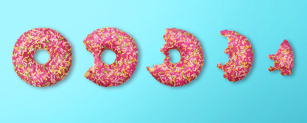 whole donut and half-eaten donuts with pink glaze and colored sprinkles on blue background