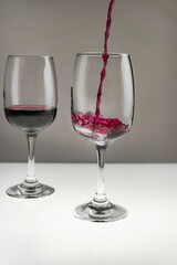 Red wine is poured from a bottle into a glass on a blurred background, close-up.
