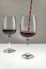 Red wine is poured from a bottle into a glass on a blurred background, close-up.