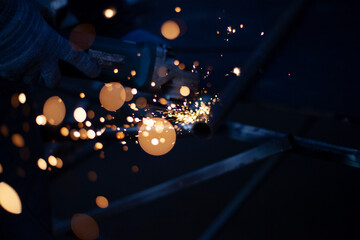 Sparks fly in all directions. Cutting metal with a grinder. Working in a metal workshop. Heating...