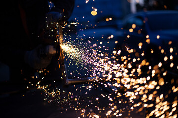 Sparks fly in all directions. Cutting metal with a grinder. Working in a metal workshop. Heating...