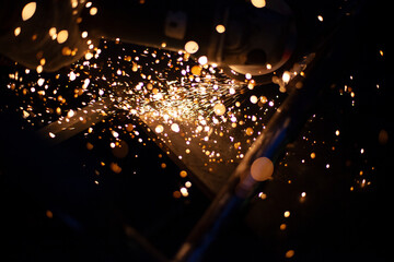 Sparks fly in all directions. Cutting metal with a grinder. Working in a metal workshop. Heating...