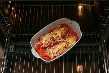 Casserole with baked bell peppers with rice, tuna, tomatoes and cheese on a grid in the oven, copy...