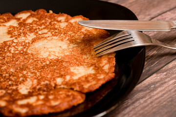 Single potato pancake with a fork and knife