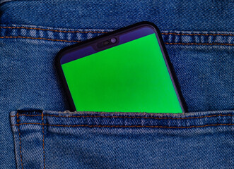 Mobiltelefon mit grünem Bildschirm in einer Hosentasche