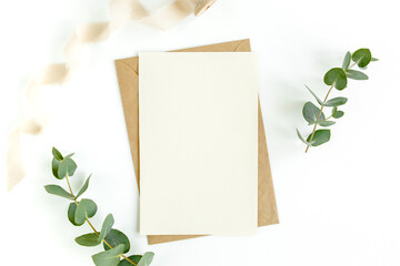 Mockup invitation, blank greeting card and green leaves eucalyptus. Flat lay, top view.