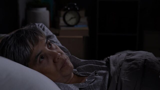 Depressed senior woman lying in bed cannot sleep from insomnia