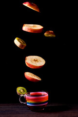Surreal creative concept with flying fruits. Slices of kiwi and apple on a black background.