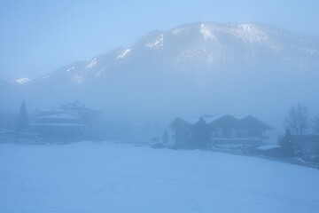 Thick fog with the sun shining through on top of the ski mountain