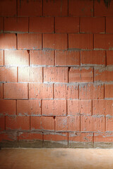Rough brick wall from Porotherm style clay blocks in a construction site laterally lit, architecture background with copy space, vertical