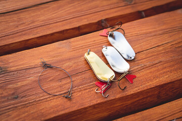 artificial metal baits on a wooden background. Homemade fishing gear. baits for catching large predatory fish. Items are made of different metal alloys of different colors and shapes