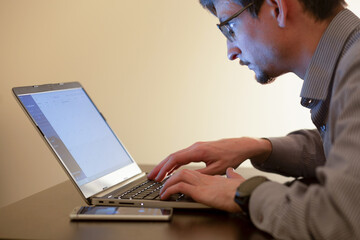 person in glasses typing on laptop