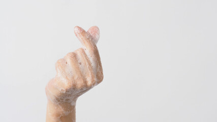 Hand doing mini heart or small heart hand sign and have foam soap bubbles on a white isolated background