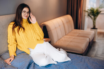 Nice girl wearing glasses and cute sweater is working freelance at home. Photo about young freelancer woman os working indoor. Student is studying online at home .