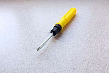 Screwdriver with yellow handle on gray background, top view, close-up, space for text