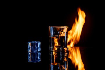 fire ice and glass of whiskey on black background
