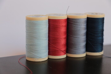 Four colors sewing threads. Red and ice, indigo and navy blue sewing threads. Sewing supplies