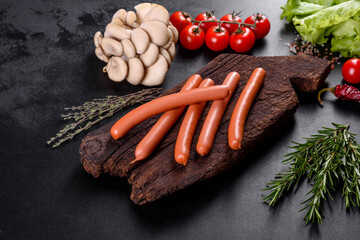 Boiled sausages on a wooden cutting board on a dark concrete background