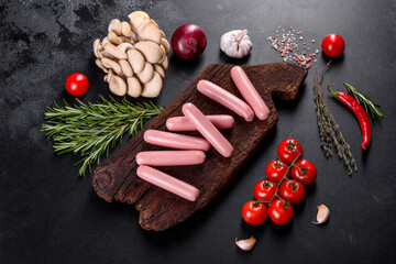Boiled sausages on a wooden cutting board on a dark concrete background