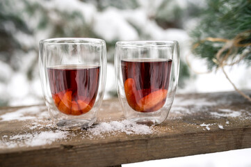 Two mugs of warm tea in the winter snow forest