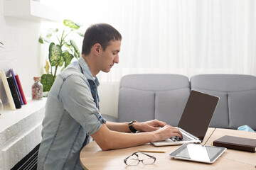 Happy young man smiling, as he works on his laptop to get all his business done early in the morning