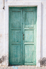 Green wooden door of a whitewashed house, typical of the town of Teguise, in Lanzarote