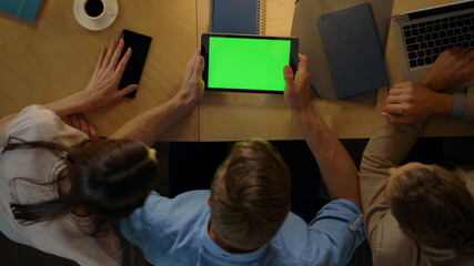 Man sitting table with colleagues. Entrepreneurs looking green screen tablet.
