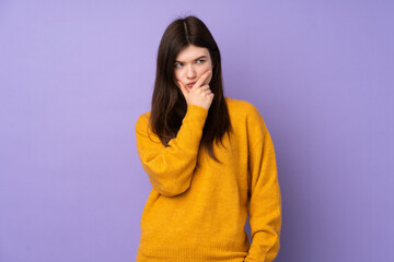 Young Ukrainian teenager girl over isolated purple background having doubts and with confuse face expression