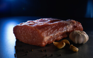 Raw meat on a gray background. A large piece of fresh mouth-watering meat with garlic and pepper. Culinary concept.