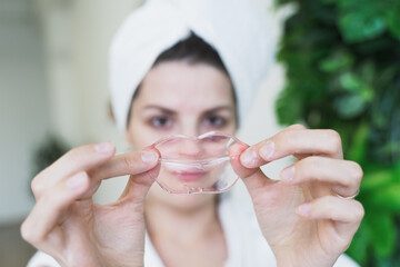 Beautiful young woman uses collagen hydrogel pink lip patch, gel mask for smooth, moisture plumped...