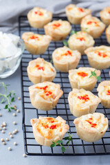 Mini quiche muffins with feta cheese, fried onion, thyme and red bell pepper, on cooling rack,  vertical
