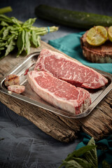 Raw rib eye steak of beef on a wooden Board with a meat cleaver and seasonings