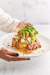 French toast stacked high and topped with salmon, lettuce, cheese, apple, whip cream and maple syrup in a warm, rustic, inviting restaurant atmosphere.