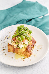 French toast stacked high and topped with salmon, lettuce, cheese, apple, whip cream and maple syrup in a warm, rustic, inviting restaurant atmosphere.
