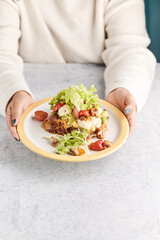 French toast stacked high and topped with salmon, lettuce, cheese, apple, whip cream and maple syrup in a warm, rustic, inviting restaurant atmosphere.