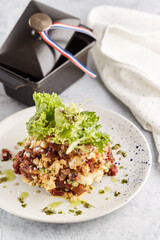  French toast stacked high and topped with salmon, lettuce, cheese, apple, whip cream and maple syrup in a warm, rustic, inviting restaurant atmosphere.