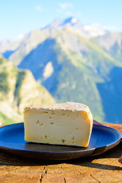Cheese collection, French tomme de savoie or tome des bauges cheese served outdoor with Alpine mountains peaks on background