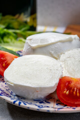 Making of fresh caprese salad with soft Italian cheese from Campania buffalo mozzarella with tomatoes, basil and olive oil