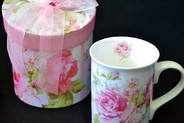 Teacup set and its flowery box on black background