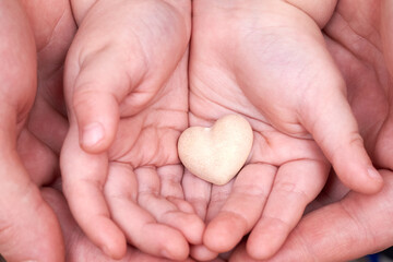 Dad and son hands hold a small plaster heart.