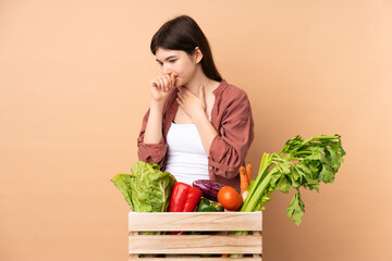 Young farmer girl with freshly picked vegetables in a box is suffering with cough and feeling bad