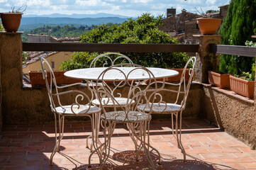 Travel destination, iron table and chairs in small ancient village Cotignac in Provence, surrounded by vineyards and cliffs with troglodytes houses.