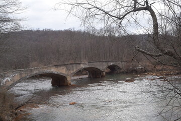 Old abandoned bridge built over the river in the woods