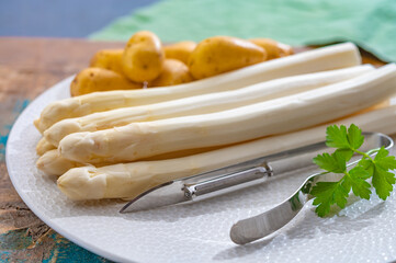 Ingredients for spring vegetarian dinner, high quality Dutch white asparagus, washed and peeled on board, ready to cookand and young potatoes