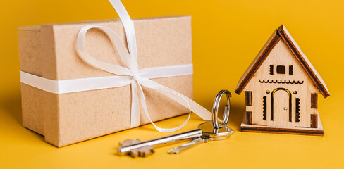 House miniature model, gift and keys on a yellow background. Investment, real estate, home, housing