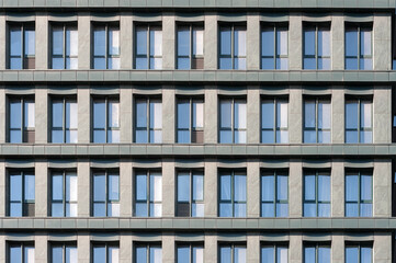 Fragment of common building facade with windows reflecting the sky