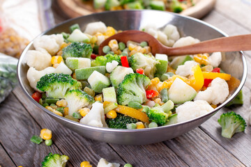 Mix of frozen vegetables in a bowl on wooden table