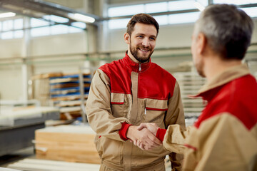 Happy male workers greeting at carpentry workshop.