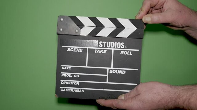 Hands with movie production clapper board on green background