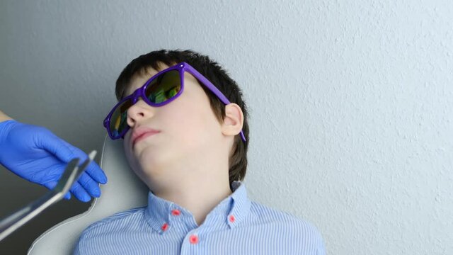 doctor examines oral cavity of small patient, molars grow, length of frenum of the tongue, boy, kid with open mouth, close up of child&rsquo;s teeth